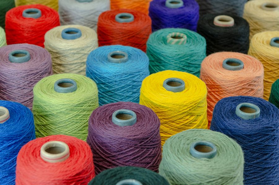 Conos de hilo acrílico reciclado en colores vivos usados en los talleres textiles de Borrissol, Mataró